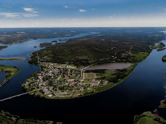 Flygfoto av Överkalix centralort omgiven av Kalix älv på sommaren